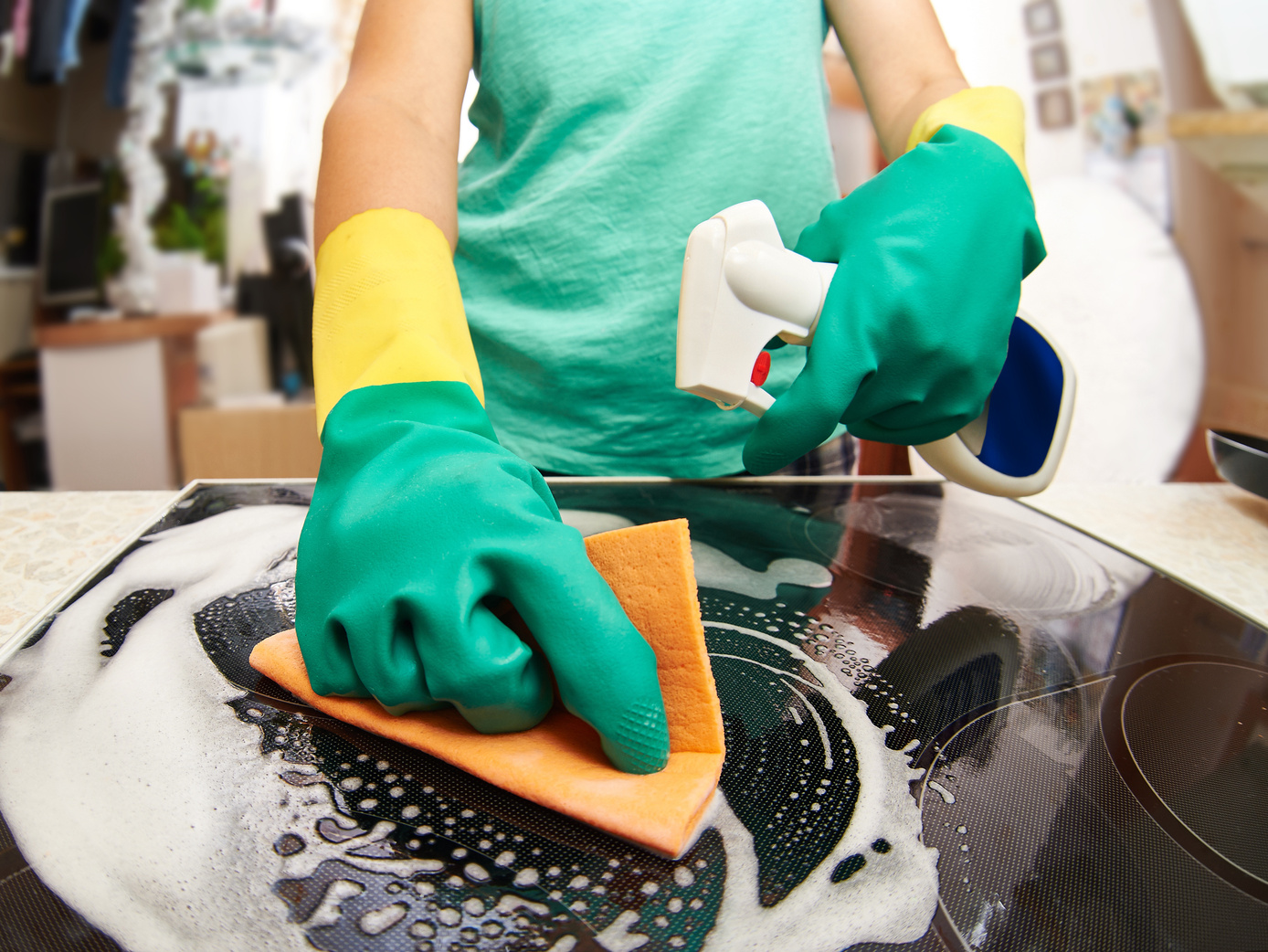 Woman cleaning stove in kitchen